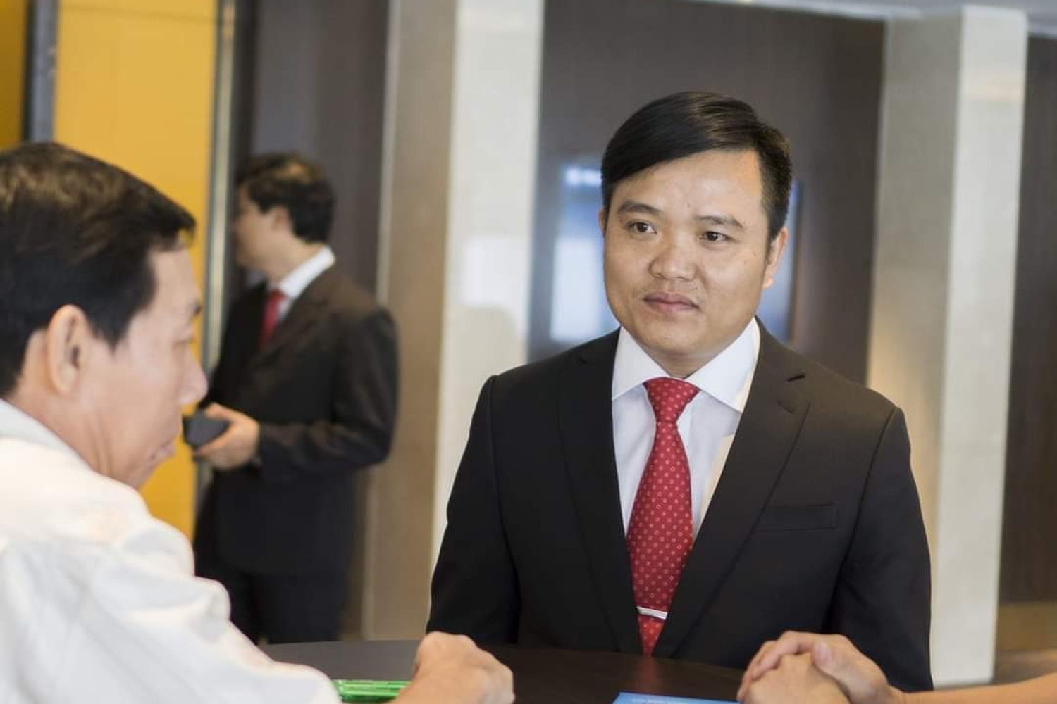 Anh Mai Đức Tuyên, Founder và CEO thương hiệu DeliFres+, mặc vest, cà vạt đỏ, trong một buổi trò chuyện